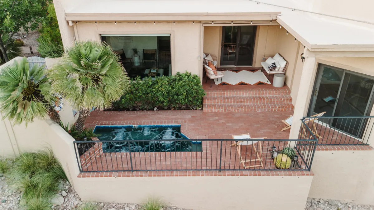 The image features a tranquil swimming pool surrounded by lush greenery and a brick patio with outdoor seating. The inviting setup is ideal for relaxation after a day of adventure, with the patio perfectly positioned for sunset views and evening gatherings.